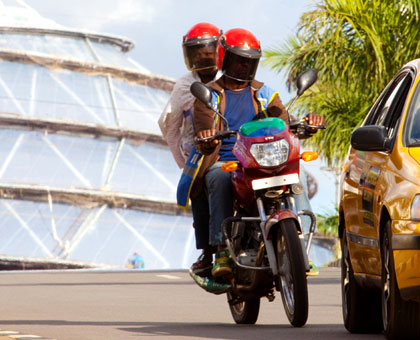 A taxi-moto rider tail-gates a taxi in Kigali yesterday. Timothy Kisambira.
