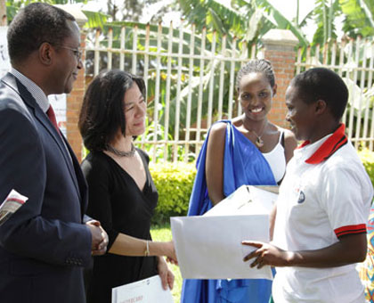 Bonifride Uwimbabazi (R) receives a scholarship notification letter from The Mastercard Foundation  President Reeta Roy, as Education minister Dr Vincent Biruta (L) looks on. John Mbanda.