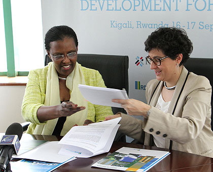 RDB's CEO Valentine Rugwabiza (L) and Arancha Gonzu00e1lez, the executive director of International Trade Centre, exchange paperwork after signing the agreement in Kigali on Tuesday. (Courtesy)