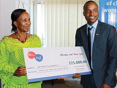 Zaina Nyiramatama, the National Commission for Children executive secretary (left), hands over a dummy cheque to Twagirayezu. The New Times / Ben Gasore.