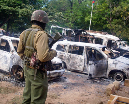 A Kenyan Police officer observes the remains of vehicles destroyed during the attack in the village of Kibaoni just outside the town of Mpeketoni, yesterday. AP photo.