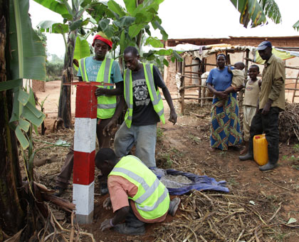 Nizeyimana and his family (R) look on as a demarcation beacon is erected in their compound in Busanza, Kicukiro District. John Mbanda. File.