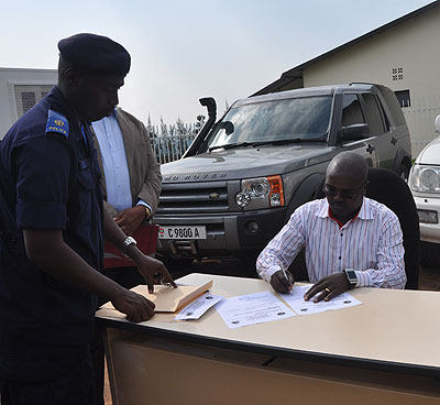 Detective Emmanuel Ngetich signs papers acknowledging receipt of the vehicles. Dean Karemera.
