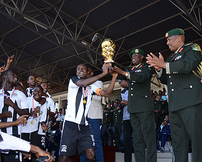 APR skipper Ismail Nshutiyamagara hands over the Peace Cup trophy to Minister of defence and clubu2019s honorary president Gen. James Kabarebe. S. Ngendahimana