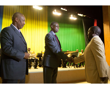 Defence minister James Kabarebe (C) hands a certificate of service to now retired Lt. Gen. Charles Muhire, as Chief of Defence Staff Gen. Patrick Nyamvumba looks on. Timothy Kisambira.