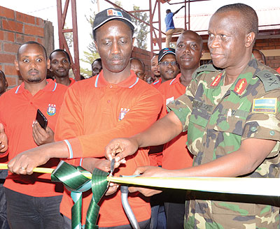 Kanyankole and Bagabo (R) cut the tape to launch the newly restocked veterans shop in Rusheshe village. 