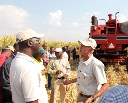 Premier Anastase Murekezi listens to irrigation specialist Keith McGaw explain how a combine harvestor operates. (Stephen Rwembeho)