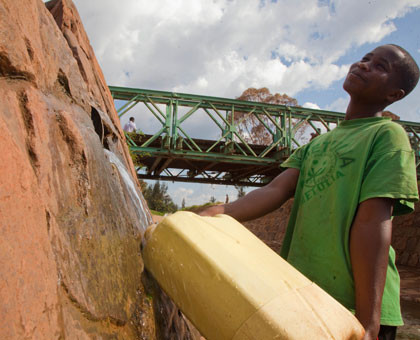 A girl draws water from an underground water system in Kimisagara. Timothy Kisambira.