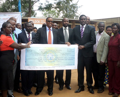 The Minister for Education, Prof. Silas Lwakabamba (C) and some of the beneficiaries of the new funding pose with dummy cheque. (Ivan Ngoboka)