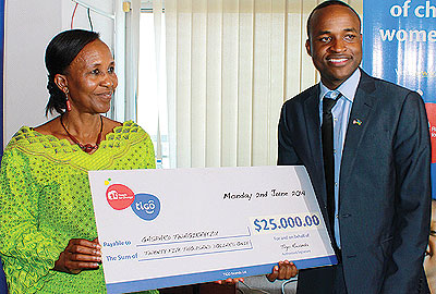Gaspard Twagirayezu (right), the winner of the second edition of the competition, receives a dummy cheque from Zaina Nyiramatama, the National Commission for Children executive secretary in June. 