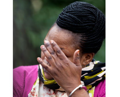 Hasifa Ddungu shields her face from cameras at Kacyiru Police Headquarters in Kigali yesterday. (Timothy Kisambira)