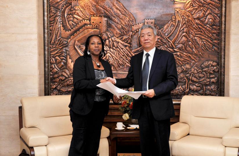 Amb. Shen Yongxiang of the Peopleu00e2u20acu2122s Republic of China (right) and Radegonde Ndejuru, Director General, Imbuto Foundation, exchange documents at the Chinese Embassy yesterday. (Courtesy)