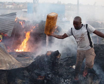 A resident of Gikondo tries to extinguish fire that burnt down businesses in the area recently. Victims of such fires can take long to be paid if they were insured by firms that under price premiums. (File)