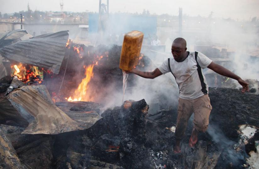 A resident of Gikondo tries to extinguish fire that burnt down businesses in the area recently. Victims of such fires can take long to be paid if they were insured by firms that under price premiums. (File)