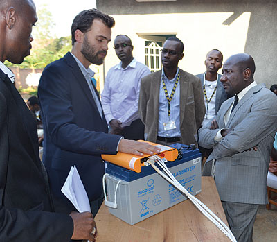 Mobisolu2019s Maier (left) explains how the solar unit works as MTN boss Asante (right) and other officials look on. The firm celebrated its 1,000th installation on Wednesday. Michel Nkurunziza.  