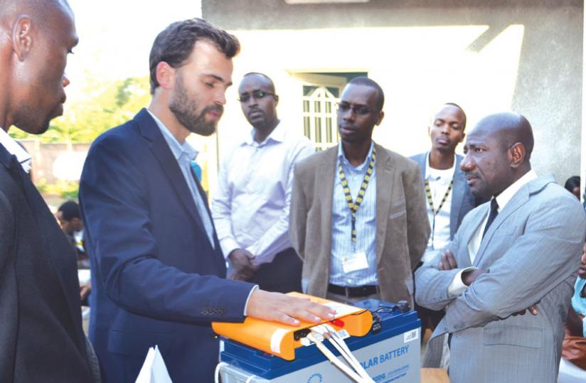 Mobisolu00e2u20acu2122s Maier (left) explains how the solar unit works as MTN boss Asante (right) and other officials look on. The firm celebrated its 1,000th installation on Wednesday. (Michel Nkurunziza)