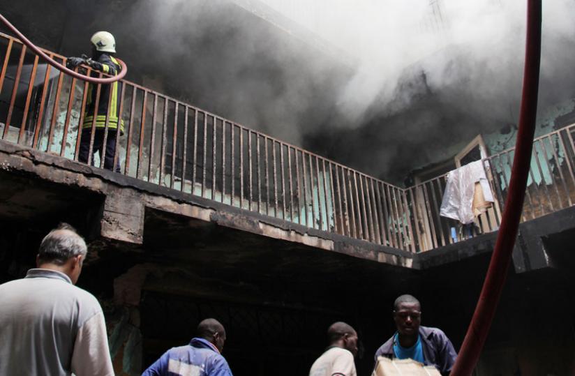 People remove property from the Muhima building as firefighters battle the raging fires yesterday. (John Mbanda)