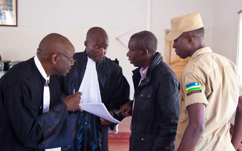 Charles Bandora (R) talks to his lawyers Boniface Nizeyimana (centre) and Ferdinand Mbera after the court session last year. (Timothy Kisambira)