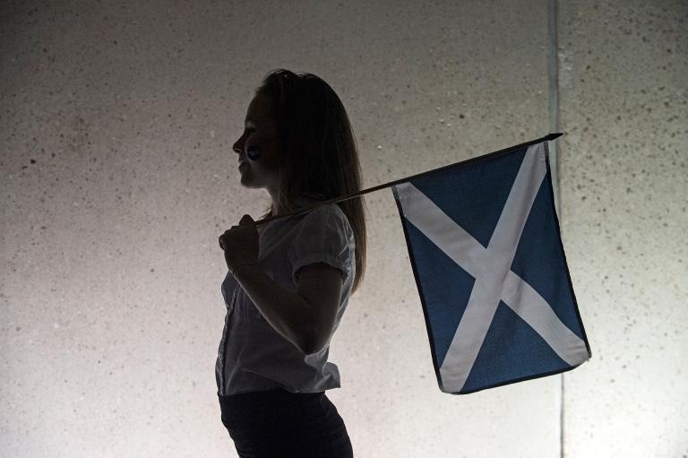 A girl holding a saltire flag, watches the entertainment outside the Scottish Parliament in Edinburgh on September 18, 2014 (AFP Photo/Lesley Martin)