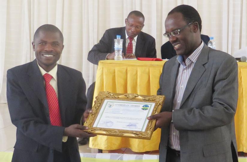 Rutunga Saccou00e2u20acu2122s Gatete (left) receives a certificate from City of Kigali mayor Ndayisaba. Rutunga is one of the six co-operatives in Kigali that were awarded for their good performance. (Michel Nkurunziza)
