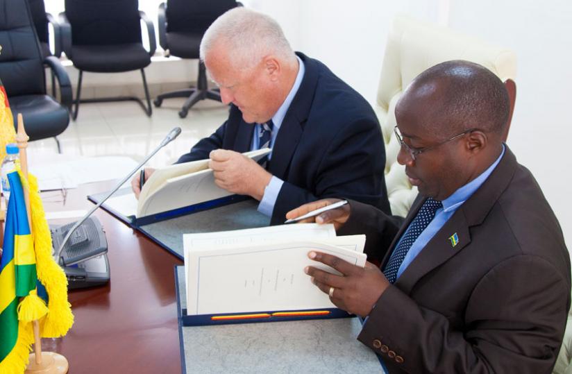 Amb. Fahrenhltz (L)  and Nzahabwanimana sign the agreement in Kigali yesterday.  (Timothy Kisambira) 