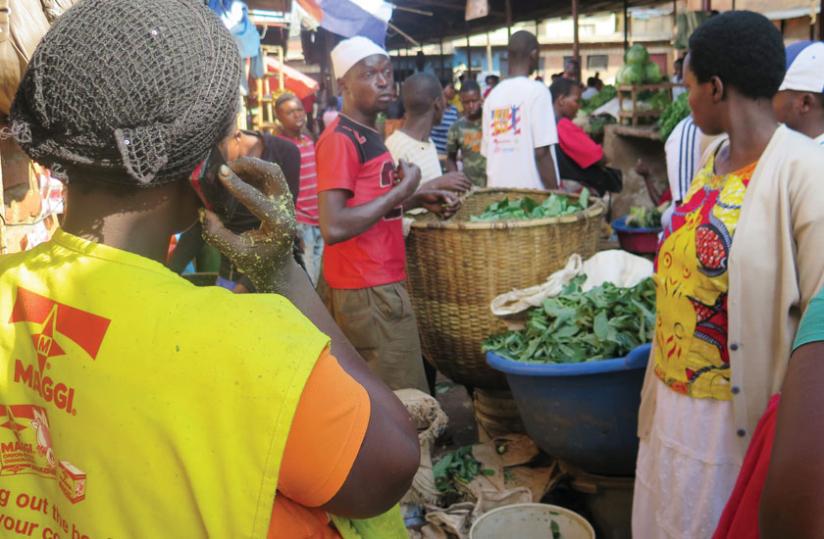 Mutamuliza (left) talks on phone as one of her workers attends to customers in Kimisagara market. (Michel Nkurunziza)
