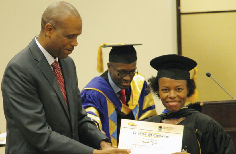 Mirenge (left) awards one of the 28 Tigo workers who graduated with MBAs last week. (John Mbanda)