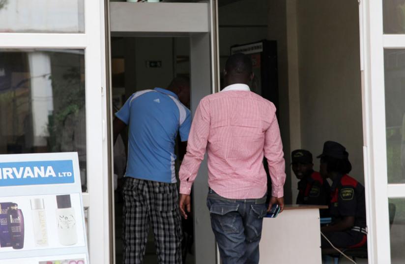 Men walk through a metal detector at the city market in downtown Kigali yesterday as two security guards look uninterested. rn(John Mbanda)