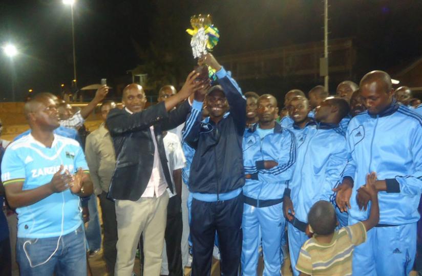 Police Coach Antoine Ntabanganyimana hoists one of the 4 trophies that they won this year. (Pontina Kabeera)