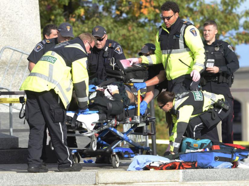 Police, bystanders and soldiers aid a fallen soldier at the War Memorial as police respond to an apparent terrorist attack in Ottawa (Internet) 