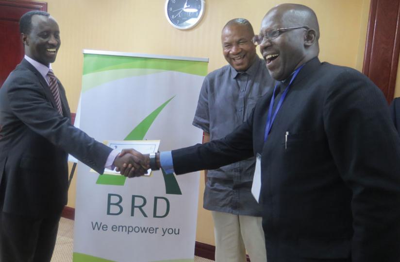 Kanyankole (left) gives one of the participants a certificate of attendance. (Emmanuel Ntirenganya)