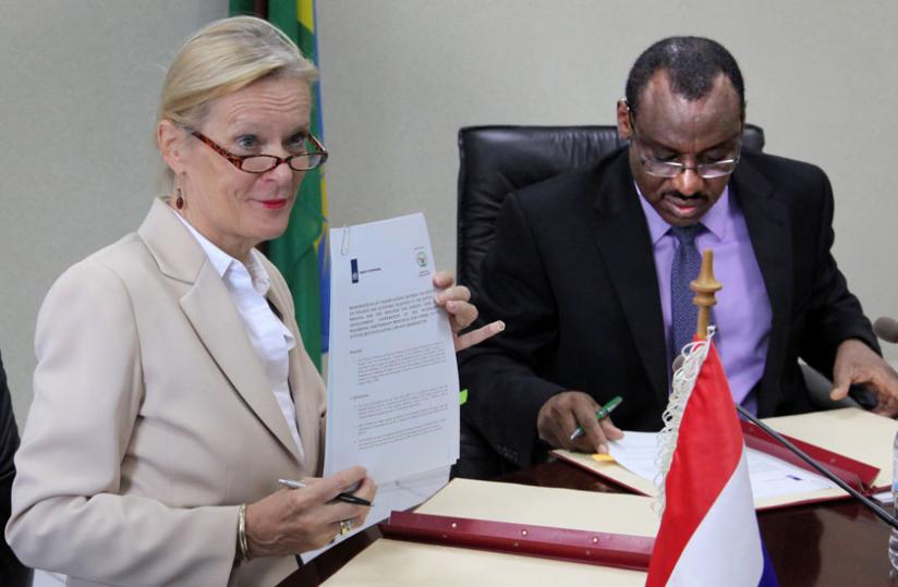 Amb. Leoni Cuelenaere of the Kingdom of Netherlands (L) shows a copy of the memorandum of understanding as Finance minister Claver Gatete signs his copy yesterday. (John Mbanda)