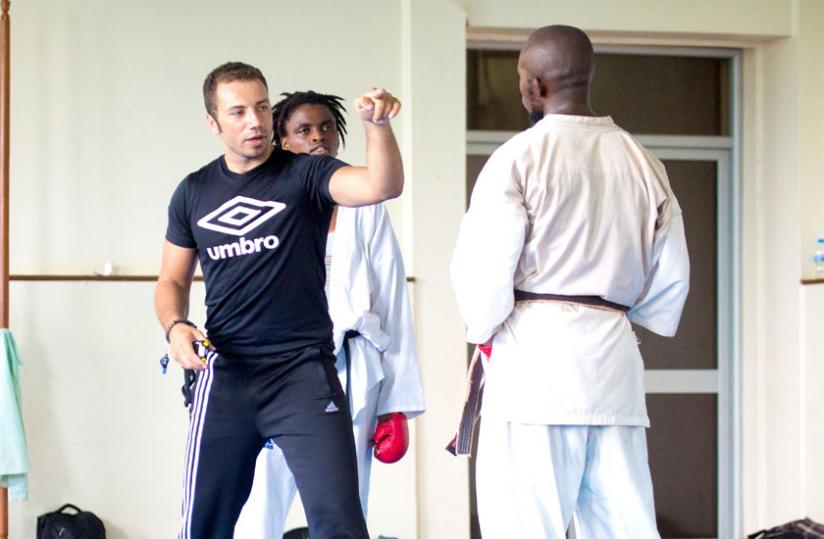 Tamer Abdel-Raouf gives Solange Ingabire (in background) tips on how to instill fear in an opponent during a training session. (T. Kisambira)