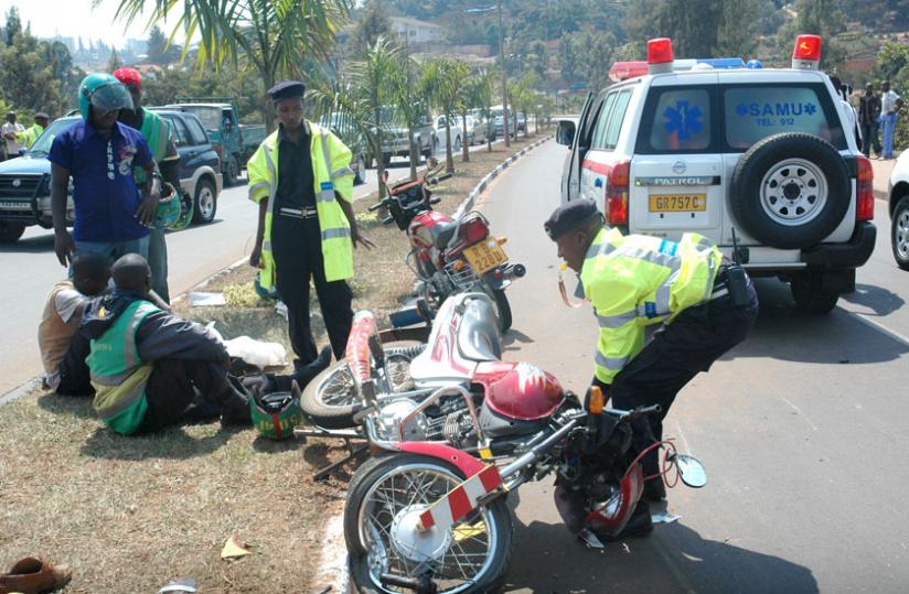 A Police officer removes a motorcycle from the scene of an accident in Kimicanga. (John Mbanda)