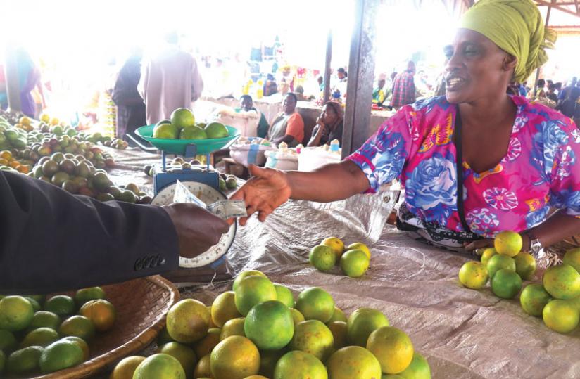 A vendor serves a buyer. Orange prices have doubled to Rwf1,000 year-on-year. (Stephen Rwembeho)