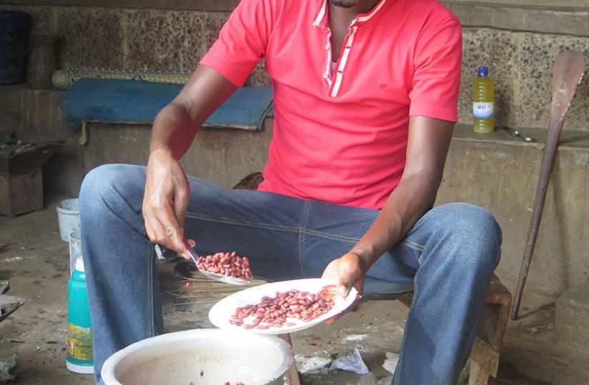 A student scoops beans for a super for him and his two housemates. Cassava and soup is the prevalent meal for needy students