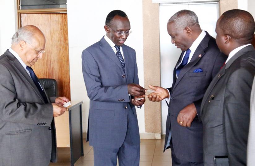 Chief Justice Sam Rugege gives out business cards to Kenyan Judges, led by Sharad Rao (left), after their meeting in Kigali yesterday. (John Mbanda)