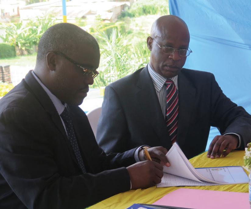 Dr Nduwayezu (left) signs a handover report as NIRDAu00e2u20acu2122s new boss Mungarulire looks on. (Ben Gasore)