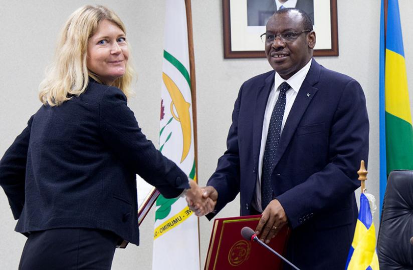 Hu00c3u00a5kansson ( L) exchanges documents with Finance minister Gatete after the signing ceremony yesterday. (Timothy Kisambira)