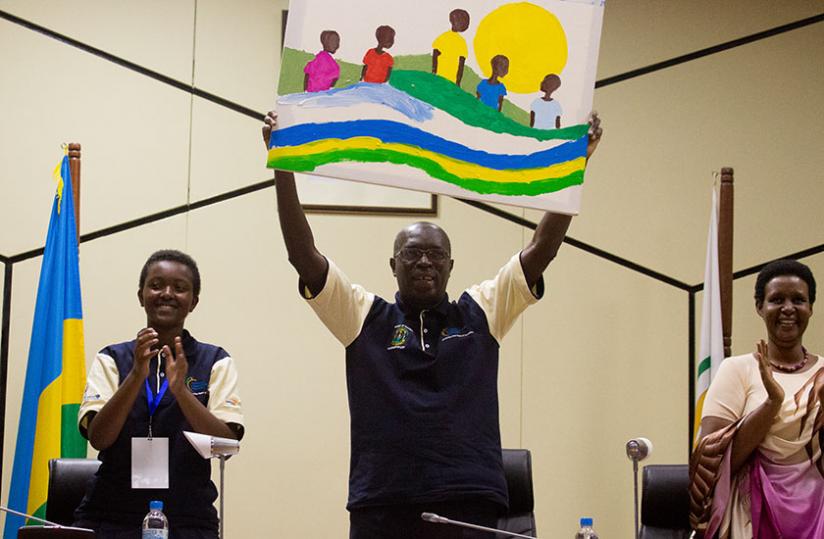 Prime Minister Anastase Murekezi holds aloft an art piece made by children during a performance on the occasion of the 10th National Childrenu00e2u20acu2122s Summit at the Parliamentary Buildings in Kigali yesterday. (Timothy Kisambira)