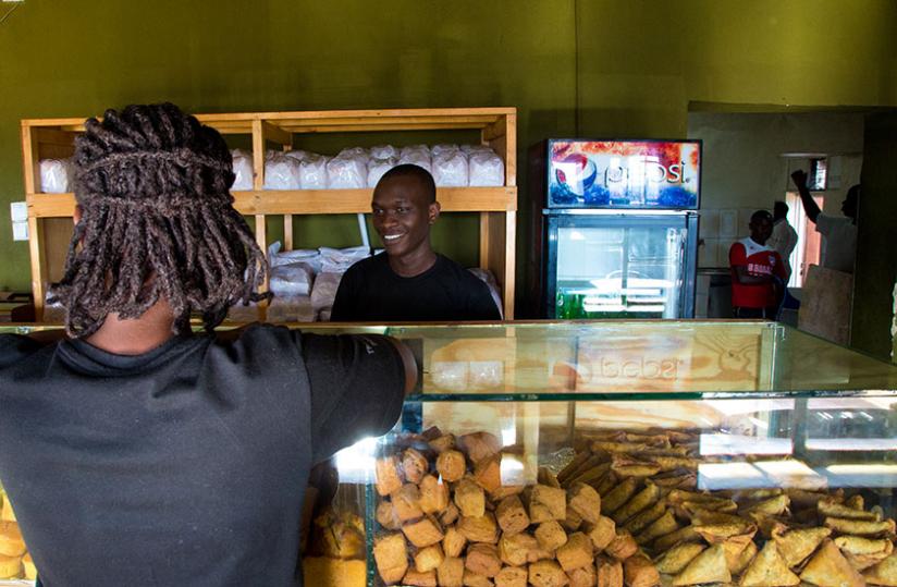 A customer pays for some snacks. (Timothy Kisambira)
