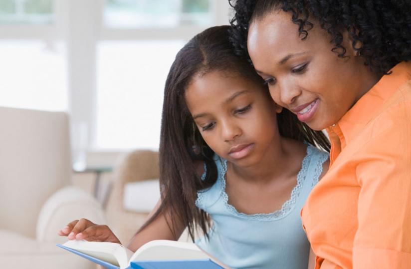 A mother teaches her daughter how to read. Most mothers say it will be challenging adapting to the revised Kinyarwanda after years of speaking the inherited version. (Internet photo)