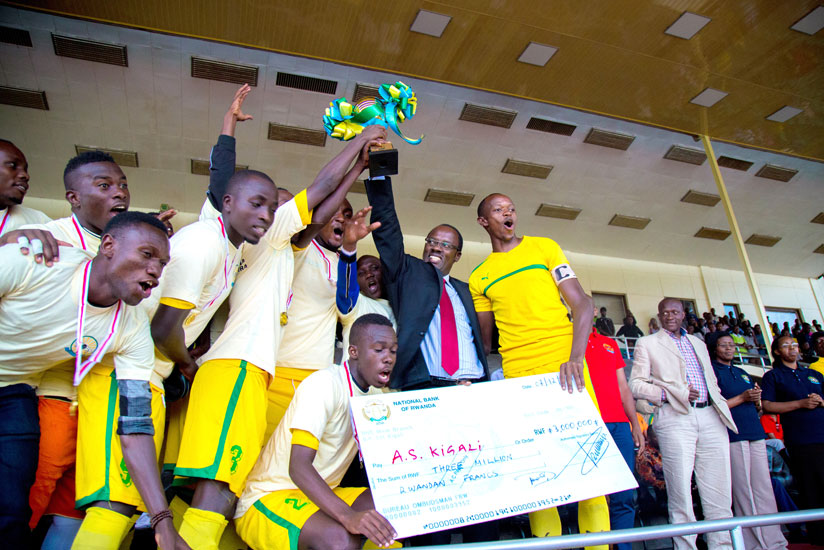 Kigali City Mayor Fidele Ndyisaba lifts the Ombudsman trophy while AS Kigali players show off the Rwf3m dummy cheque that they won after defeating Police 1-0. On the extreme right is Sports Minister Joseph Habineza and the Ombudsman Mrs. Aloysie Cyanzayire. (Timothy Kisambira)