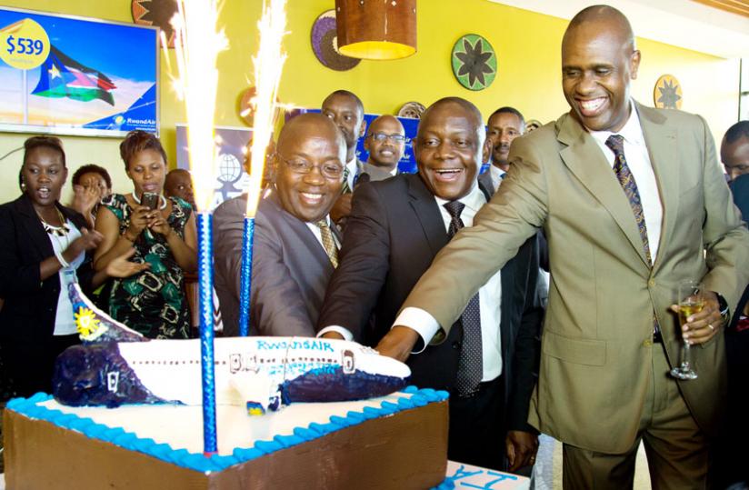 Cutting the cake, from left to right; the State Minister for Transport, Alexis Nzahabwanimana, International Air Transport Association vice-president for Africa Raphael Kuuchi, and RwandAir chief executive John Mirenge at the IOSA certificate ceremony at Kigali International Airport yesterday.(Timothy Kisambira)