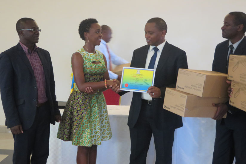 Hirwe (second left) receives a certificate from Olivier Rwamukwaya, the State Minister in charge of Primary and Secondary Education. (Solomon Asaba)