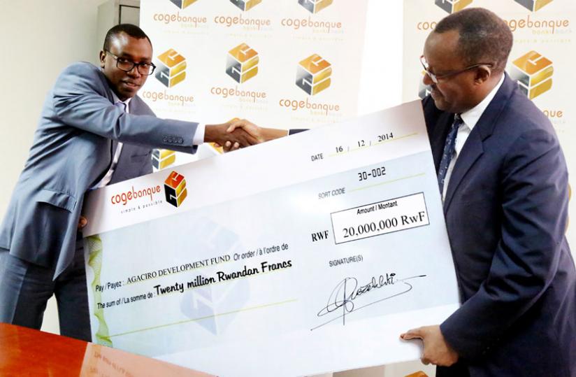 Agaciro Development Fund's Kagabo (R) receives a dummy cheque from Mujyambere yesterday. (John Mbanda)