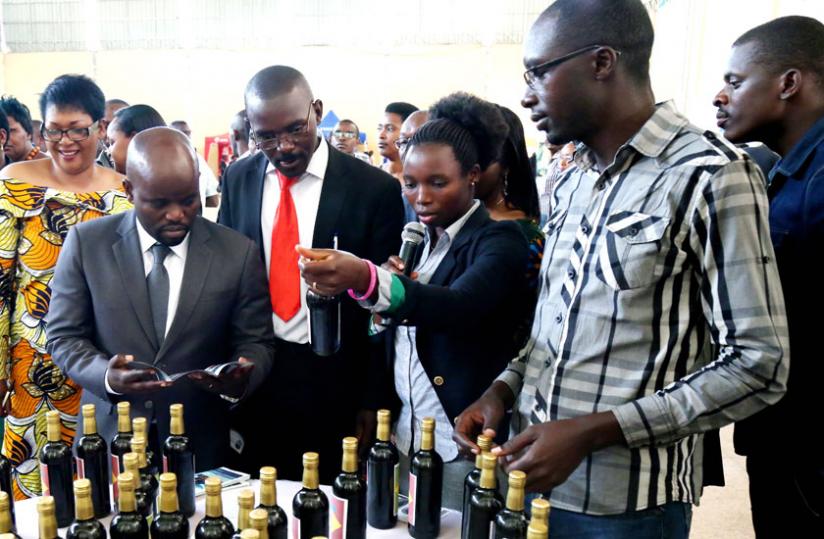 Youth and ICT minister Jean Philbert Nsengimana (L) and other officials look at pineapple wine made by Coprodemu, a Muhanga-based youth cooperative, during the annual 2014 YouthConnekt Convention at Petit Stade in Remera, Kigali, yesterday. (John Mbanda)