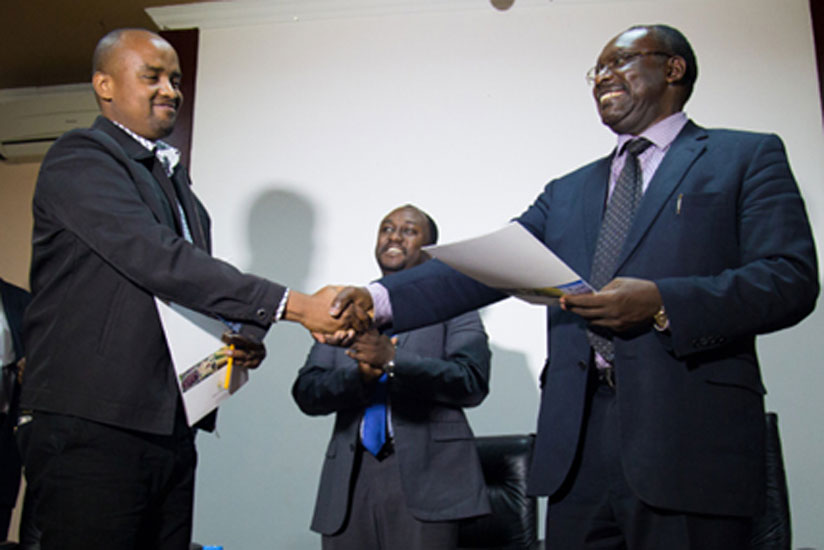 Product Development Manager East African Granite Industries Christian Mugisha (L) exchanges documents with minister Kanimba as Evode Imena looks on. (Timothy Kisambira)