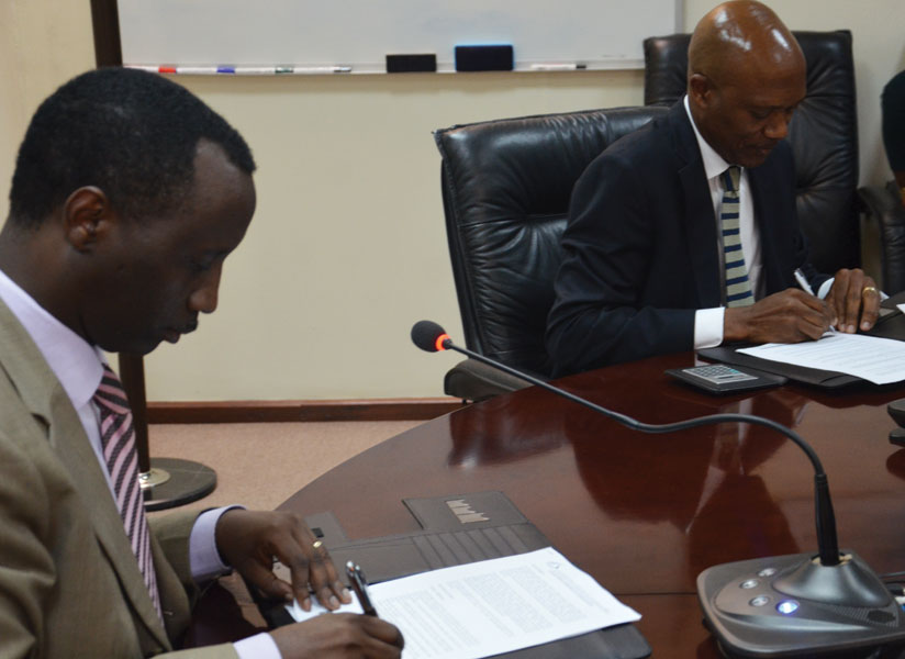 Kanyankole (left) and Tineyi sign the loan deal at BRD offices on Wednesday. (Peterson Tumwebaze)