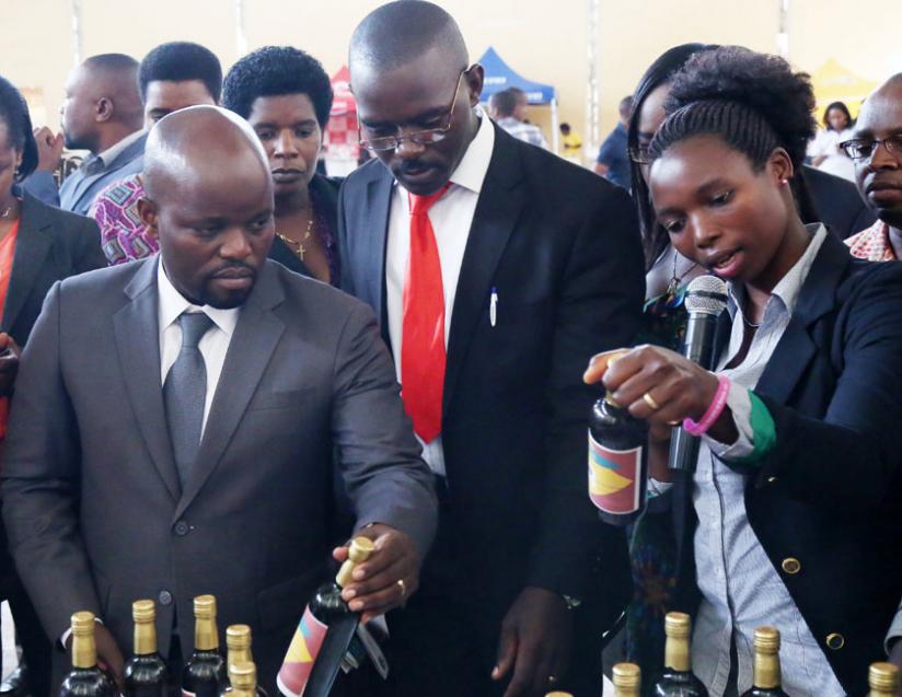 Nyiramajyambere explains to Youth and ICT minister Jean Philbert Nsengimana (left) and national youth council coordinator Norbert Shyerezo (centre) how pineapple wine is manufactured, during an exhibition in Kigali on December 17, 2014. (File)